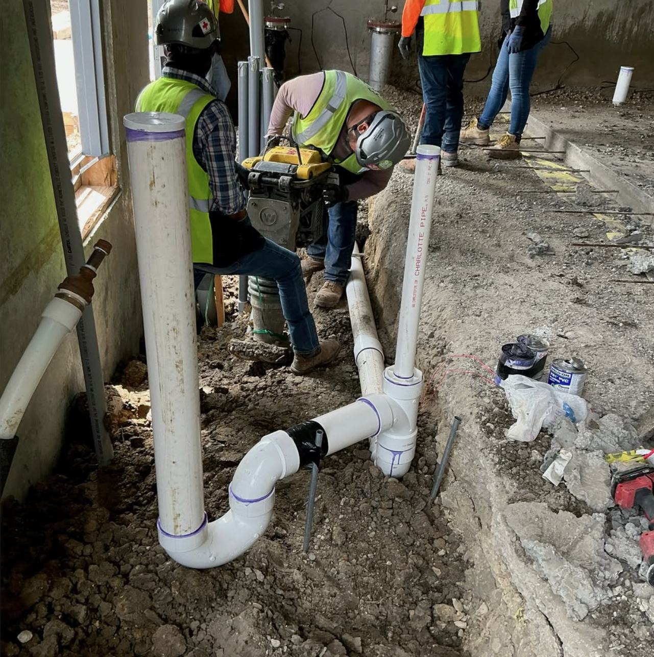 Plumbers installing commercial sewer pipe in a trench